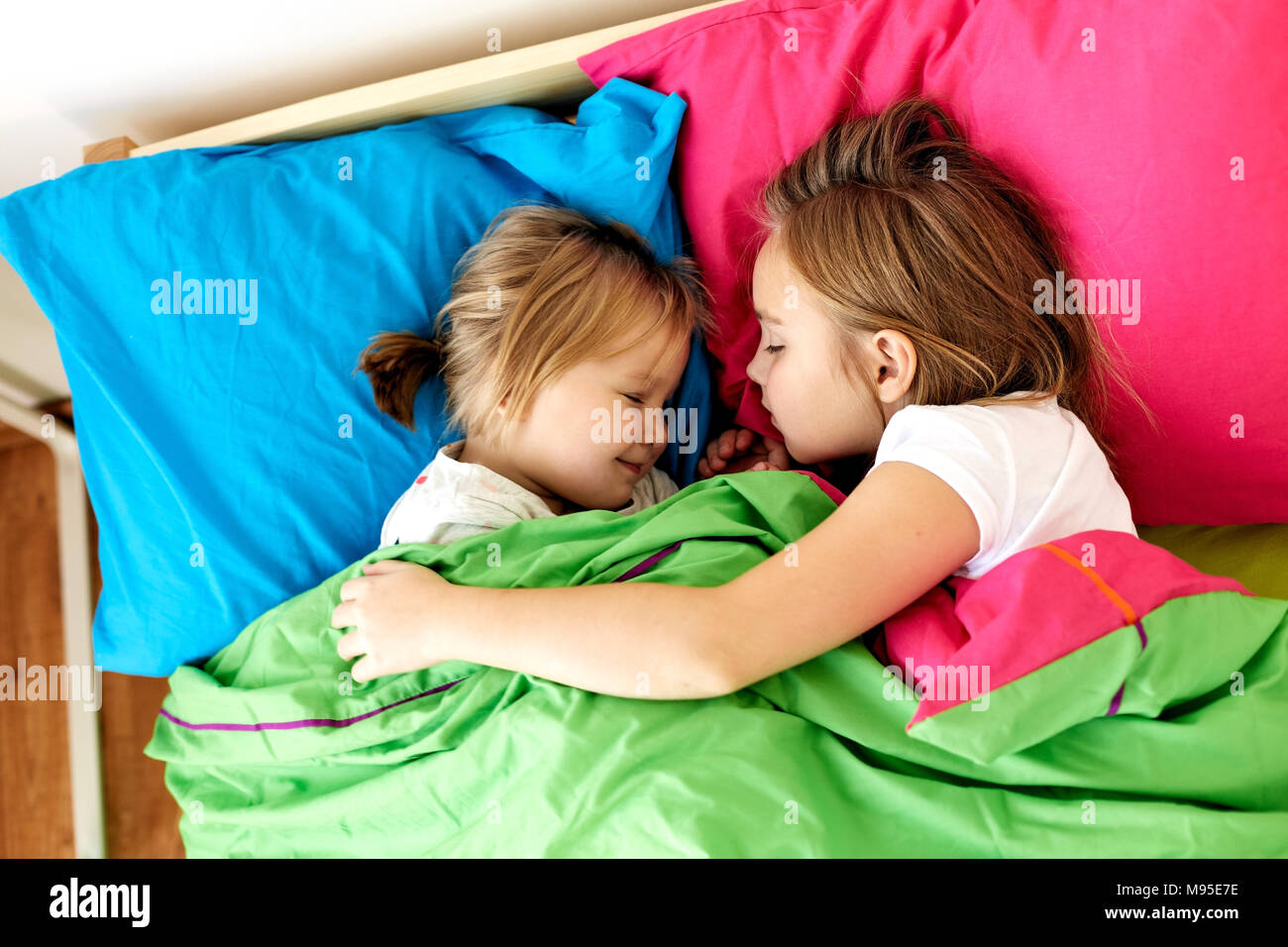happy little girls sleeping in bed at home Stock Photo