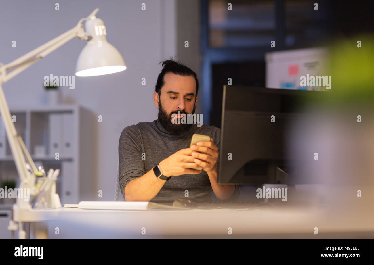 creative man with smartphone at night office Stock Photo