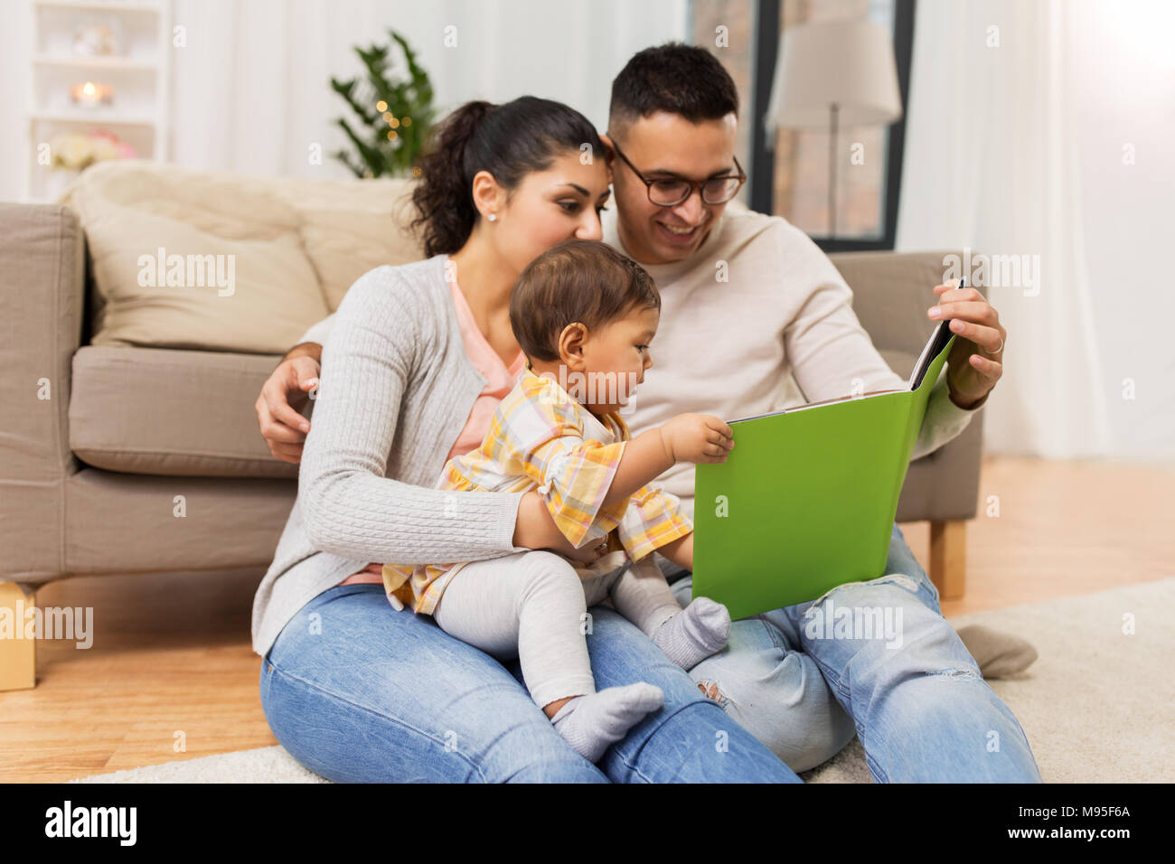 happy family with baby reading book at home Stock Photo