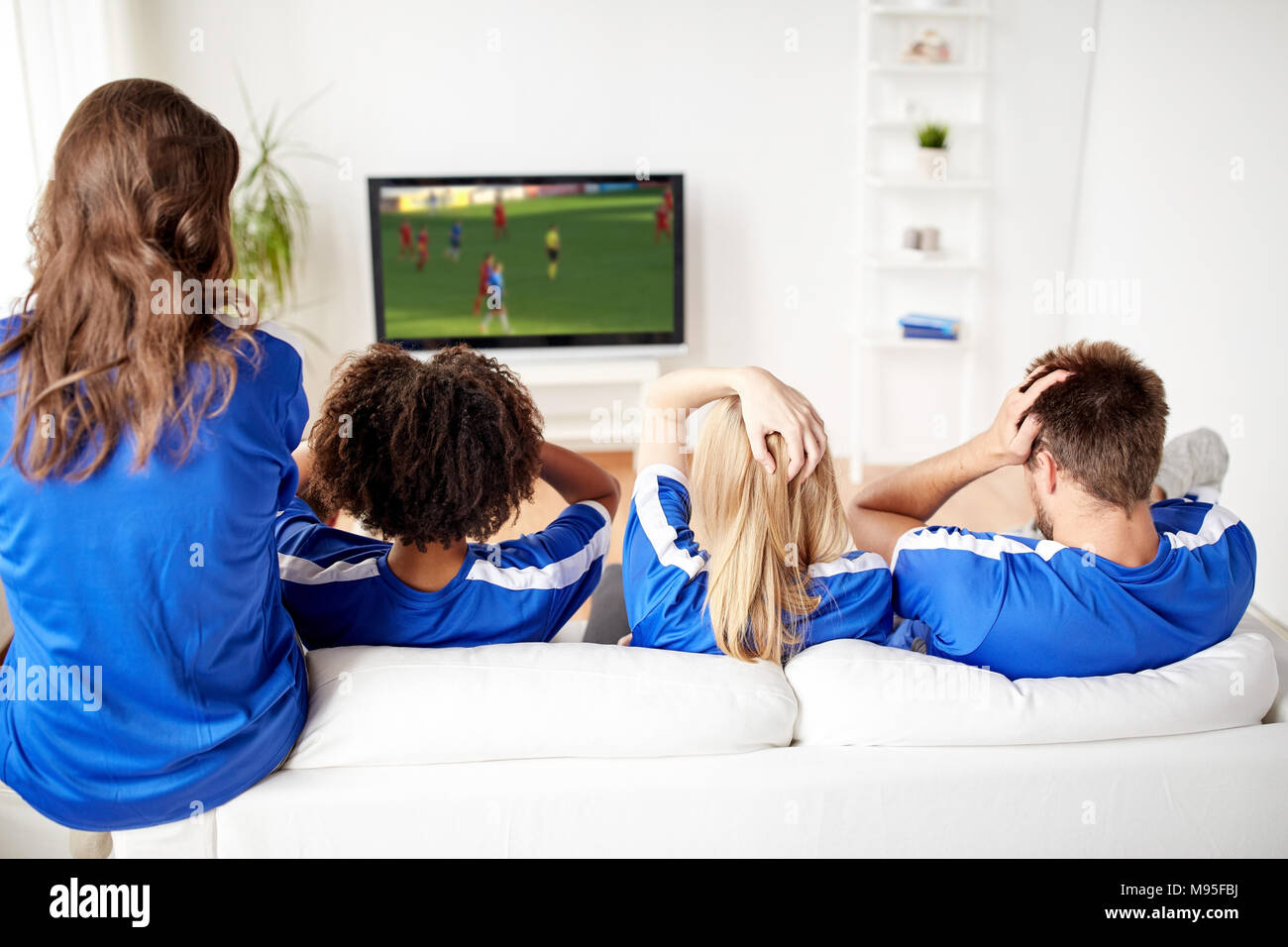football fans watching soccer on tv at home Stock Photo