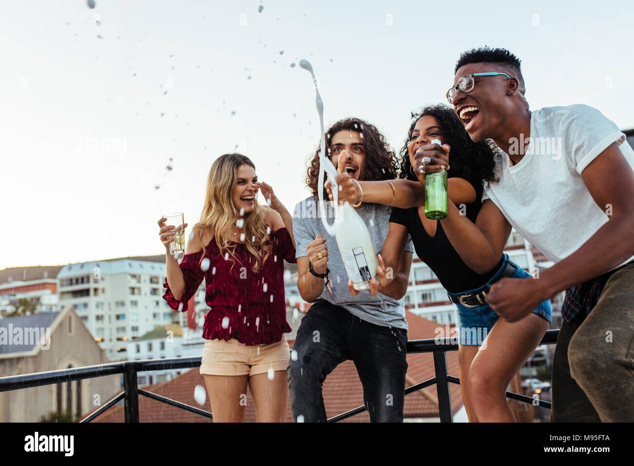 Diverse group of friends celebrating party with champagne.  Men and women having a great time at the rooftop party. Stock Photo