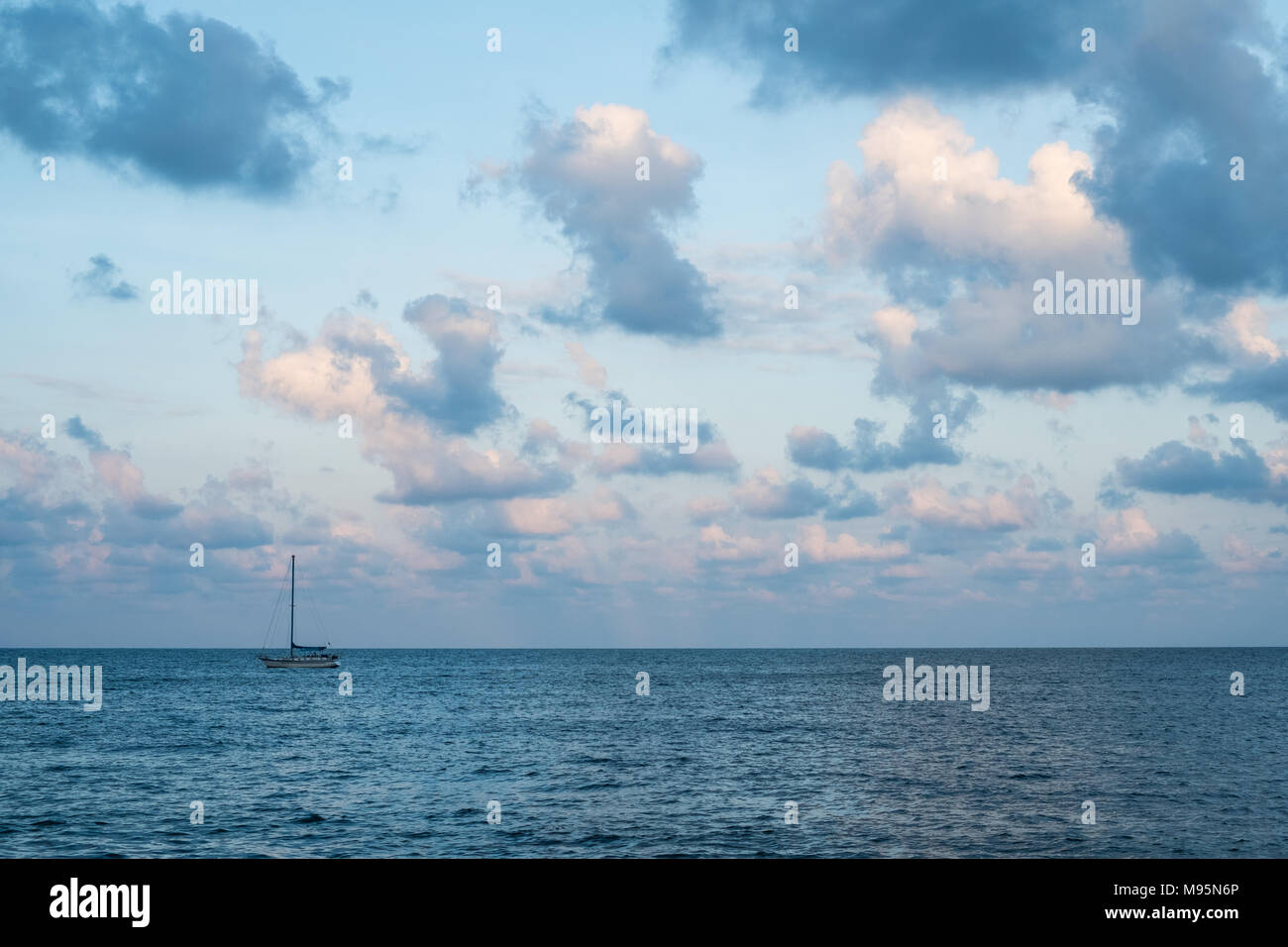scenic sky over ocean - colorful clouds and sailing boat on horizon - Stock Photo