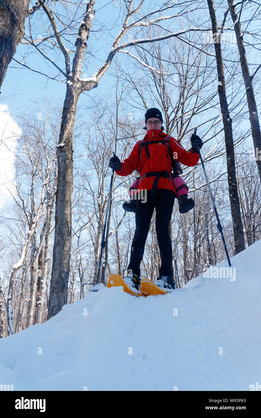 A mother snowshoeing in Quebec Canada with her three year old child on her back Stock Photo