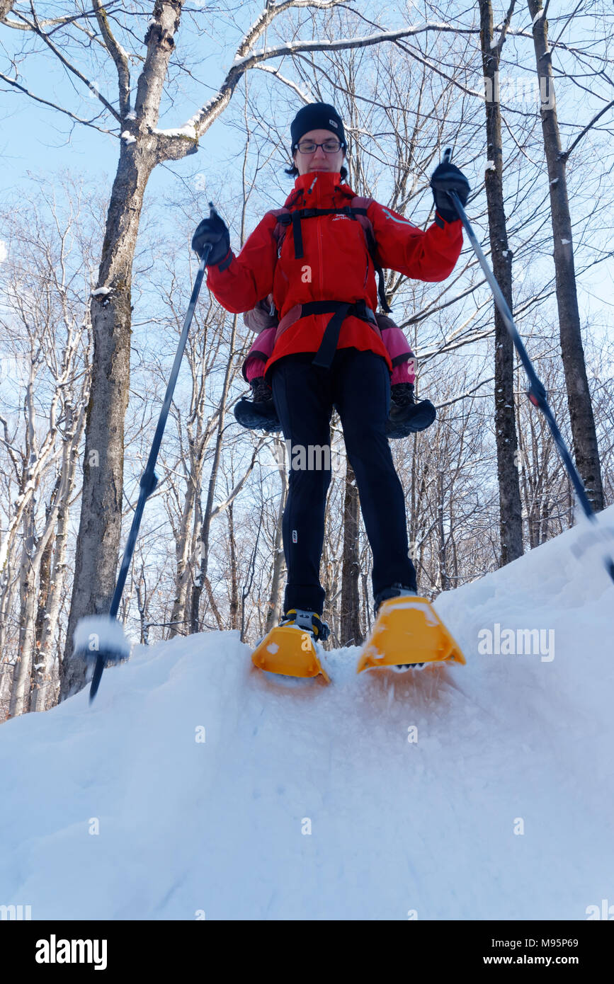 A mother snowshoeing in Quebec Canada with her three year old child on her back Stock Photo