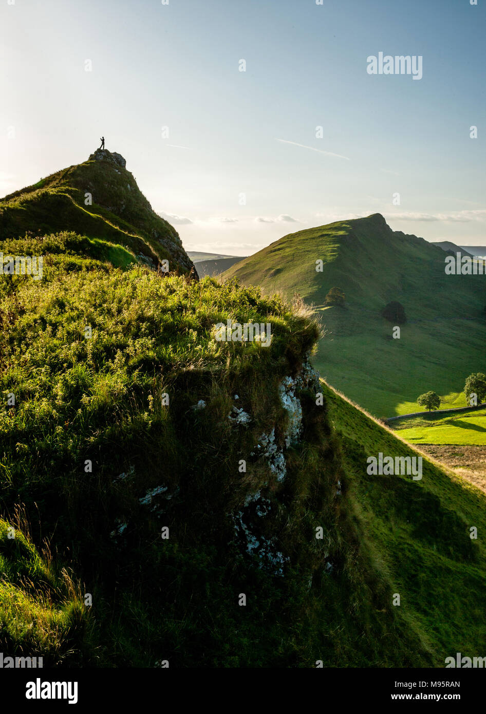 Walker on the summit of Parkhouse Hill looking across to Chrome Hill and the Dragon's Back in upper Dovedale in the Peak District National Park UK Stock Photo