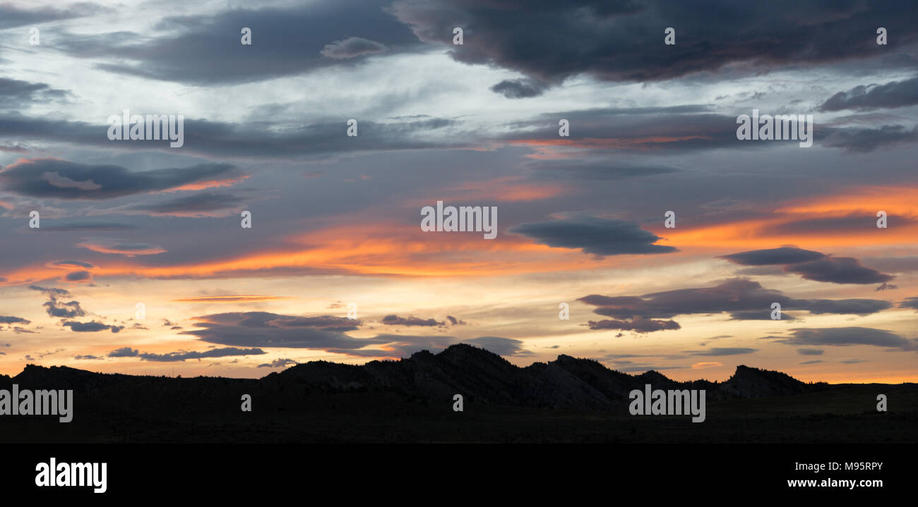 Sunset over Yellowstone western hill country grey clouds orange sections Stock Photo