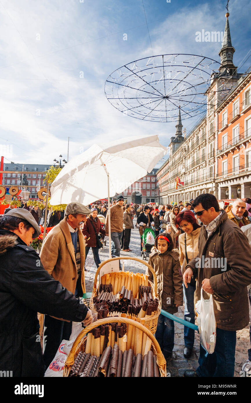 Madrid, Spain : Family buying barquillos traditional wafer sweets at the Christmas market in Plaza Mayor square  designed by Juan de Villanueva in 179 Stock Photo