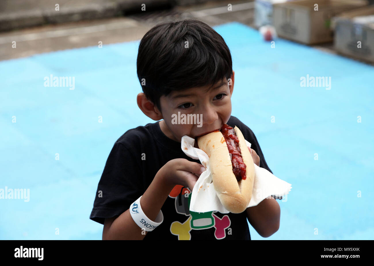 Little HUngry Eurasian Boy Eating a Hot-dog with appetite Stock Photo