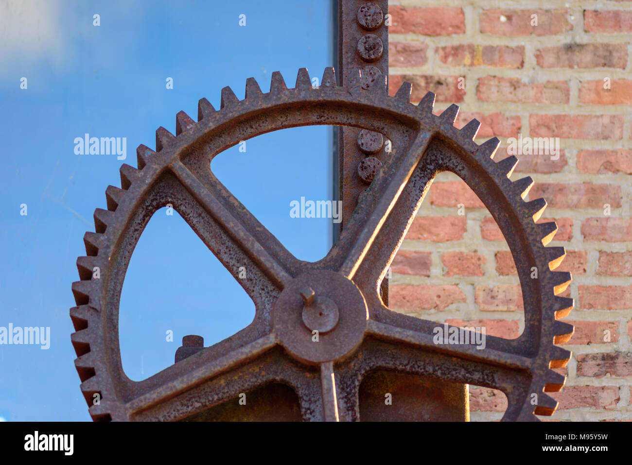macro closeup of rusted old steel gear outside of historic brick factory Stock Photo