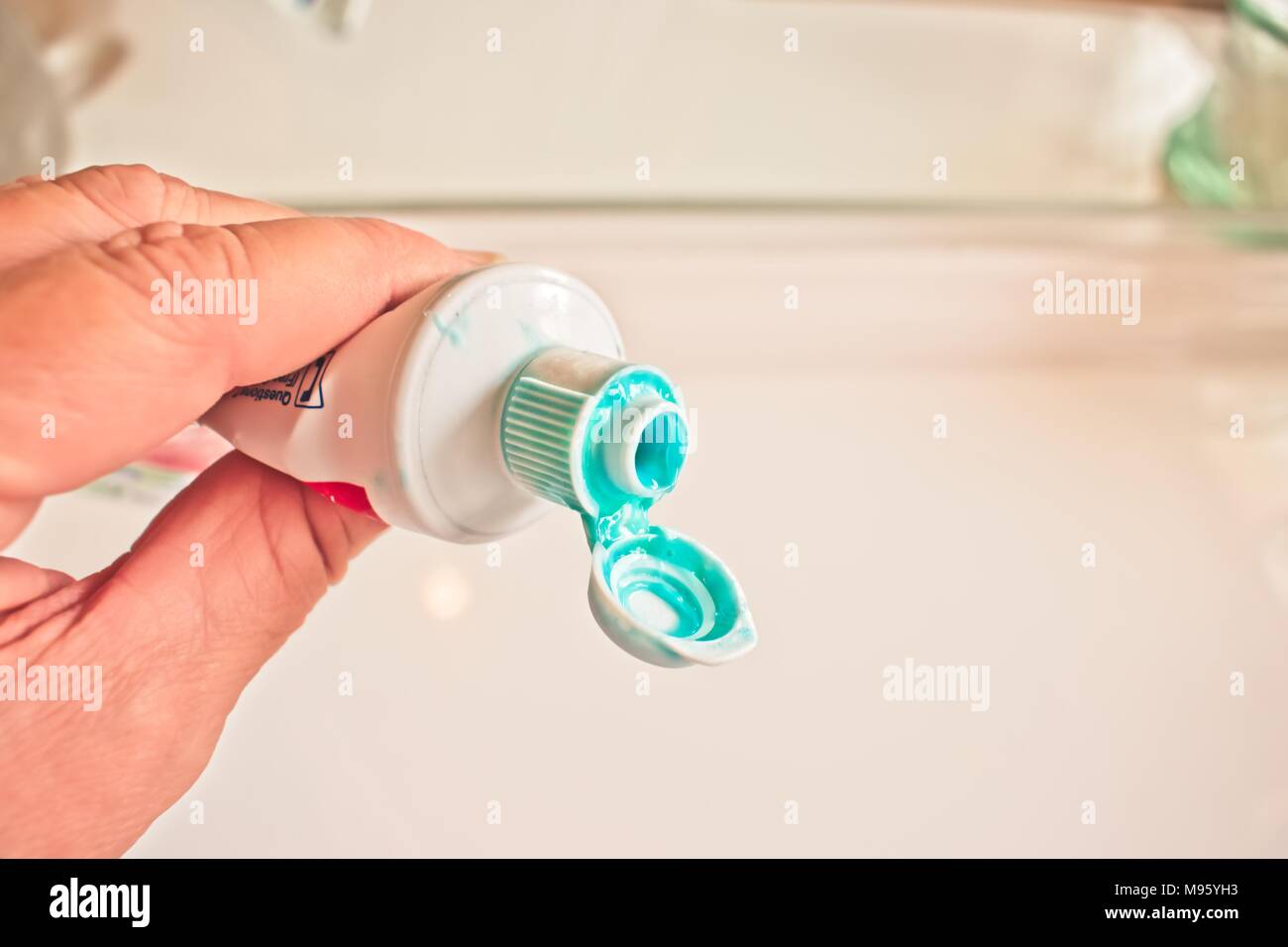 Hand holding a messy toothpaste tube Stock Photo