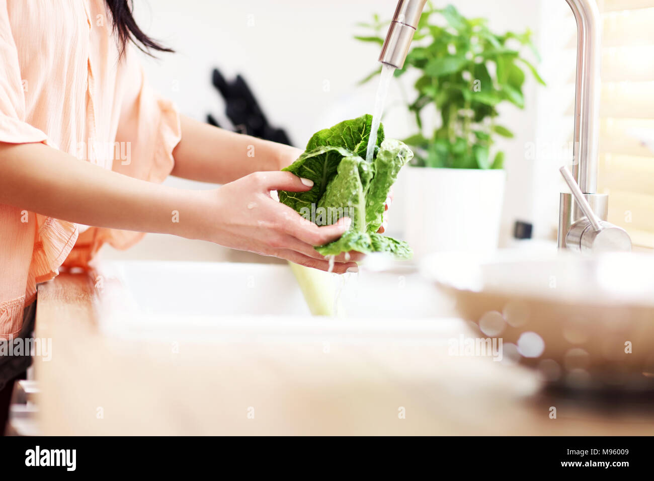 Young woman washing lettuce in modern kitchen Stock Photo