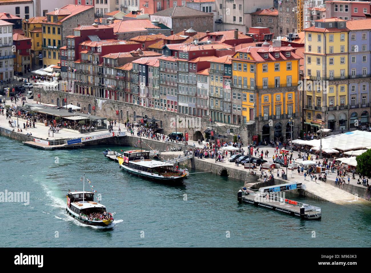 Douro River cruise boat with tourists passing Cais da Ribeira promenade and square, Porto, Norte Region, Portugal Stock Photo