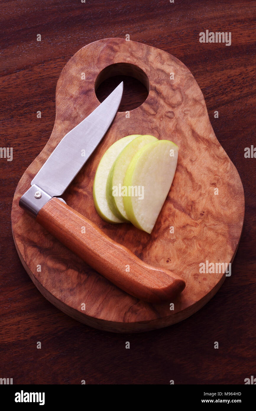 Cut and sliced apple with folding fruit knife on an olive wood board