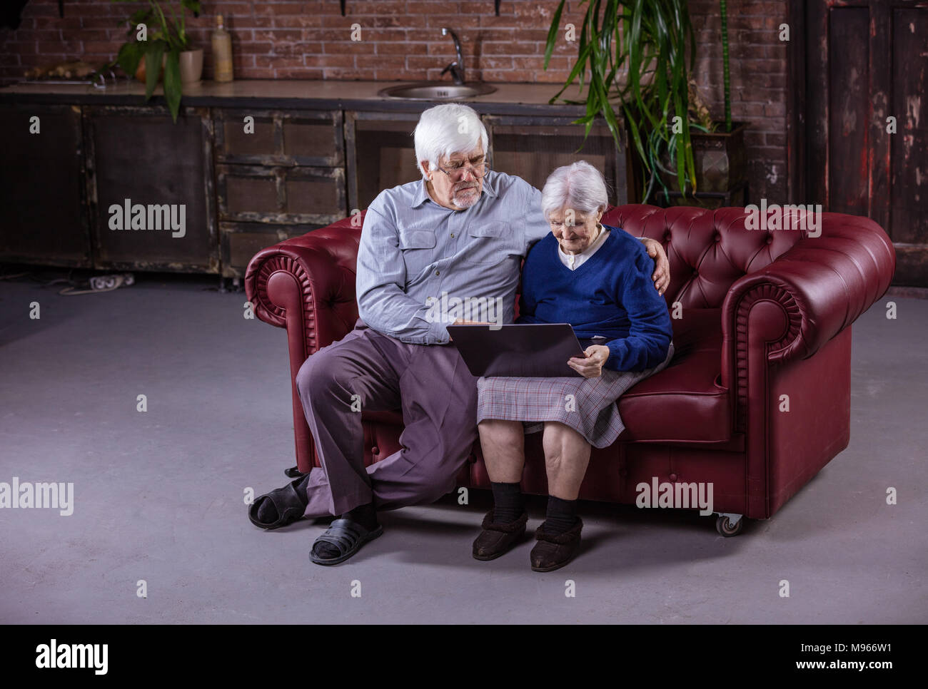 Senior couple using laptop while sitting on couch at home Stock Photo