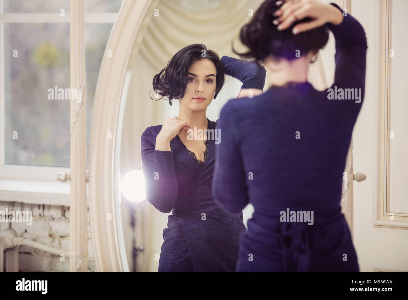 Portrait of beautiful young woman looking in mirror Stock Photo - Alamy