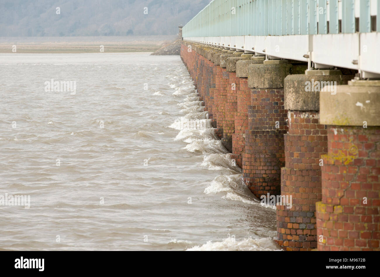 A large, spring flooding tide meeting Arnside viaduct, Cumbria England UK. Arnside is situated on the Kent estuary which narrows and results in strong Stock Photo