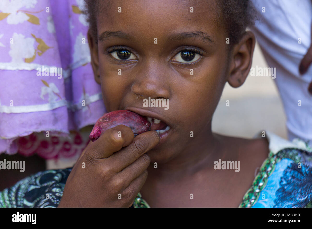 young girl eating a star apple, Chrysophyllum cainito, in Zanzibar Stock Photo