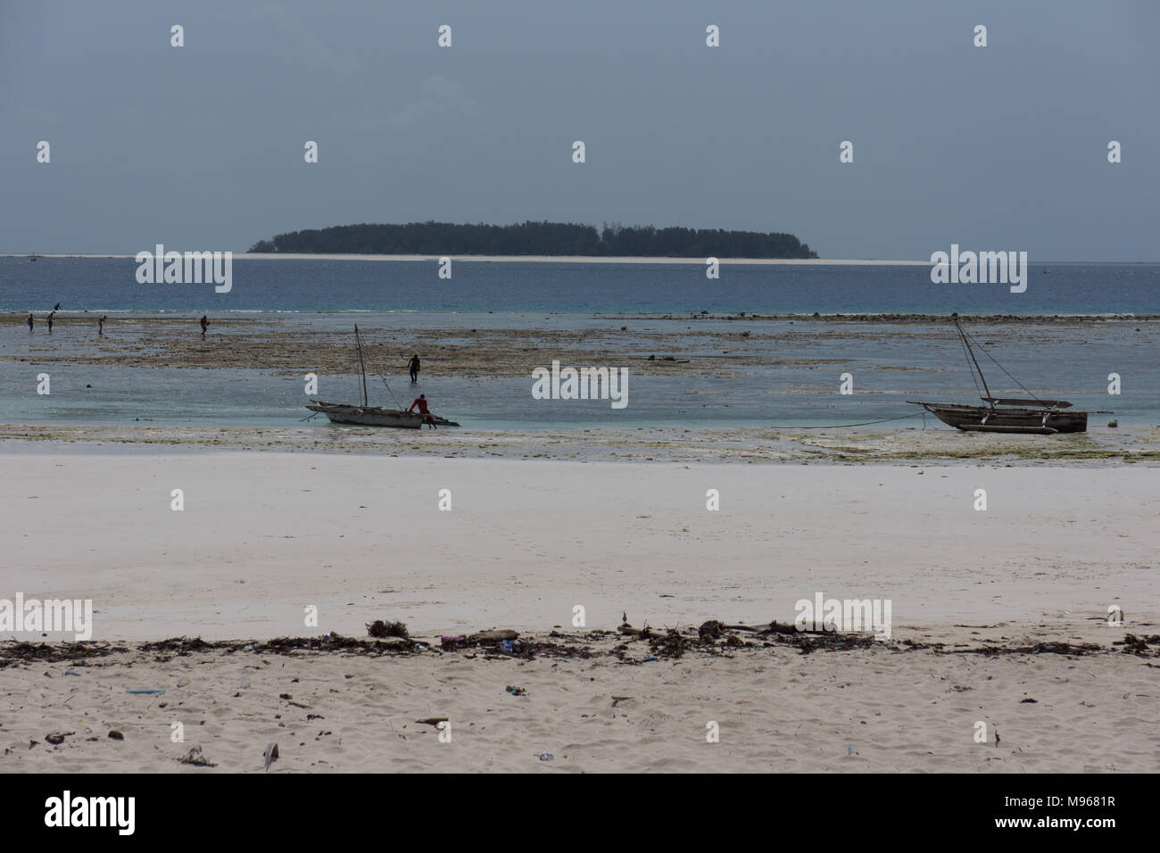 Traditional fishing boats beached with Mnemba Island in the background Stock Photo