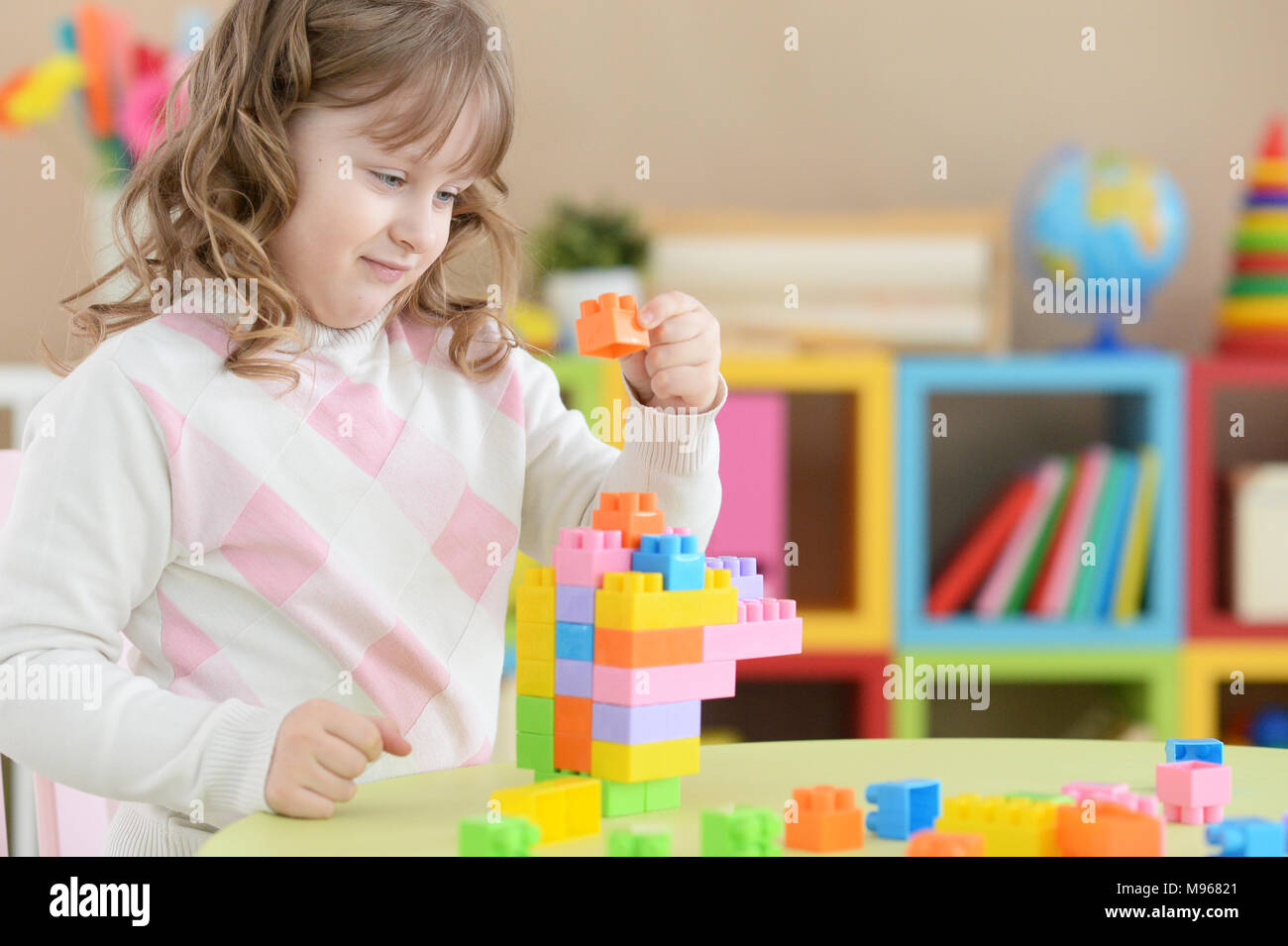 Cute little girl playing with colorful plastic blocks in room Stock ...