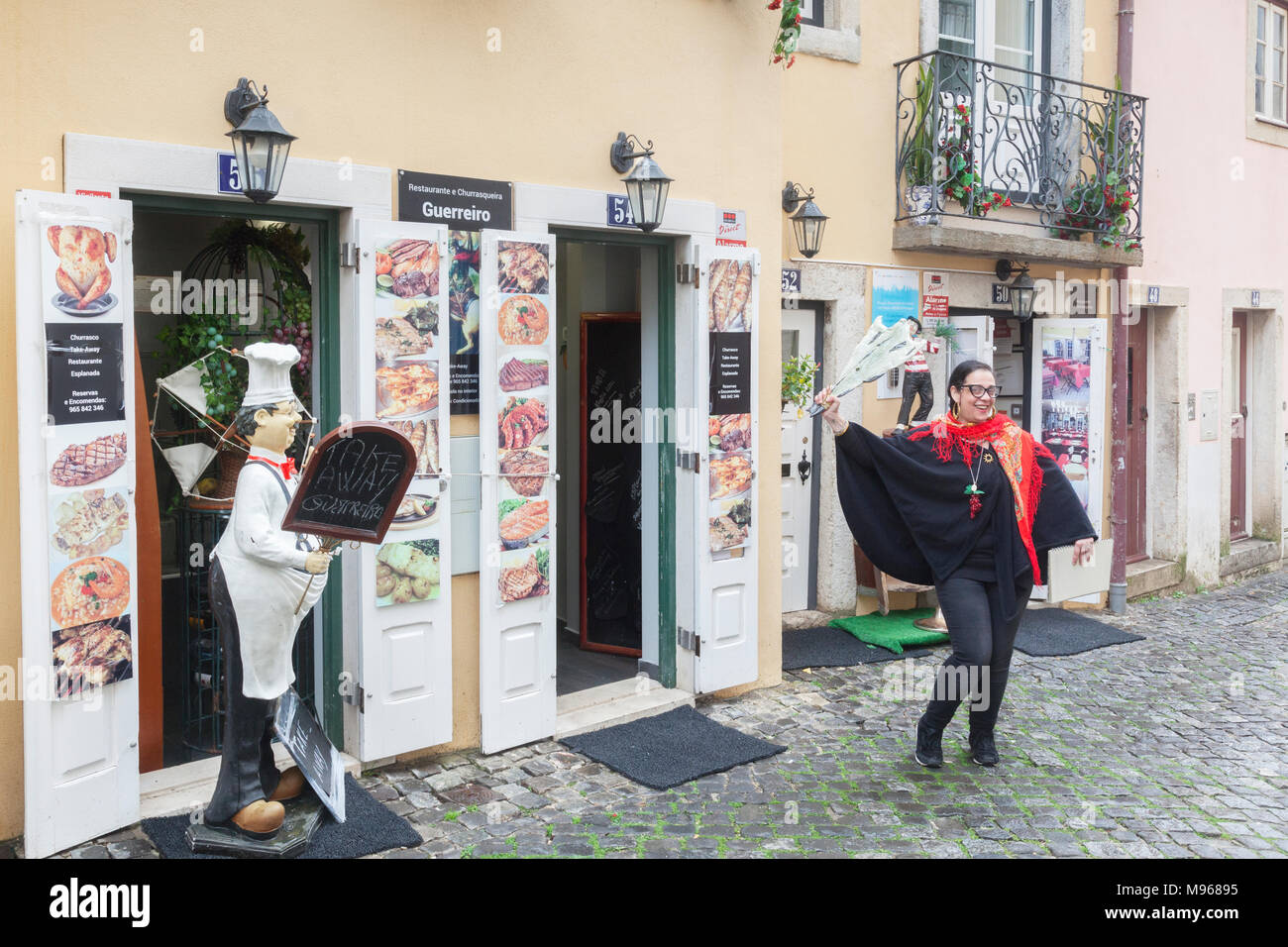 1 March 2018: Lisbon, Portugal - A young woman attracting business outside Restaurant Guerreiro in Lisbon Old Town. She is brandishing a piece of... Stock Photo