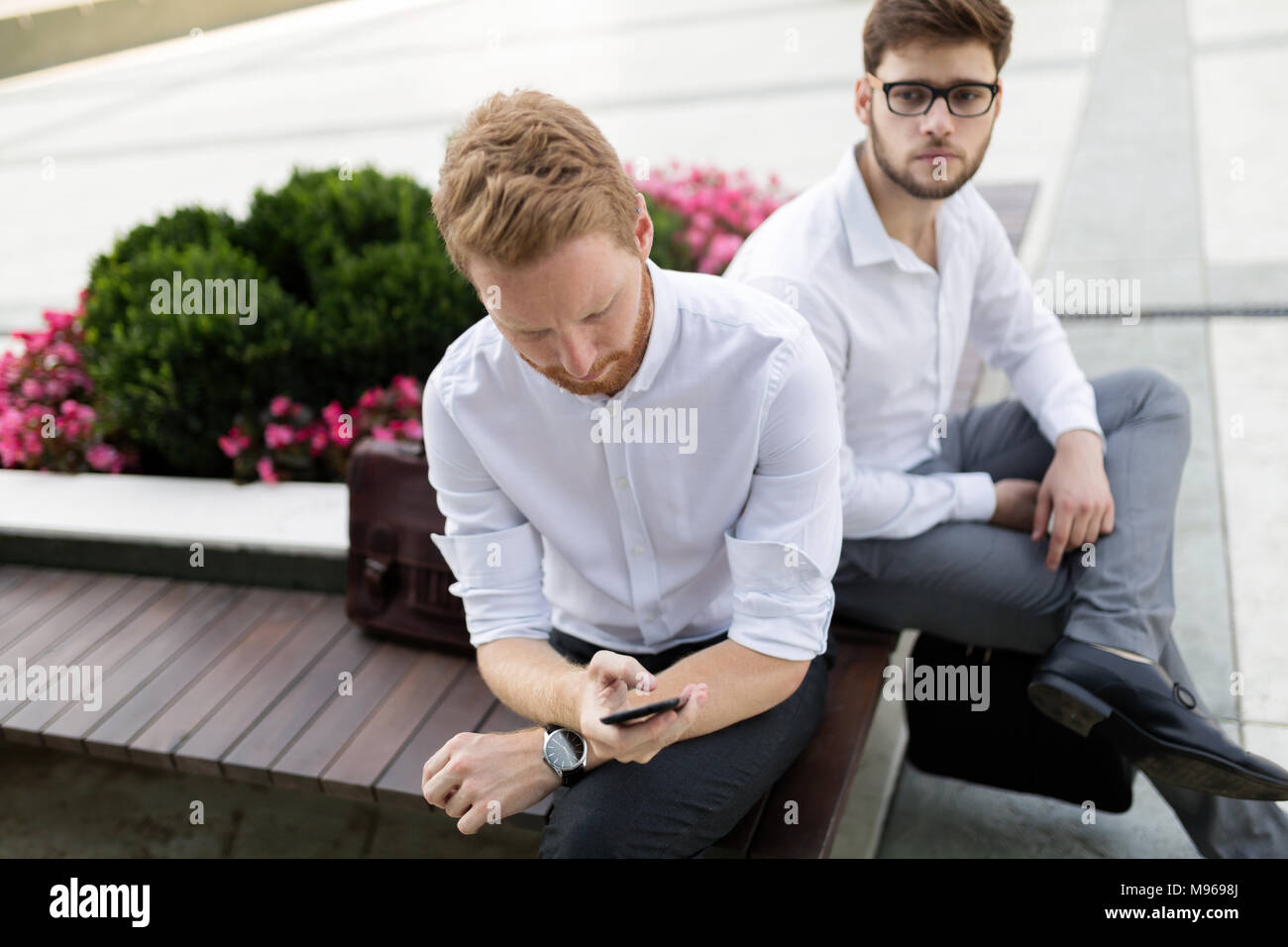 Business colleagues sitting on bench outdoors Stock Photo - Alamy