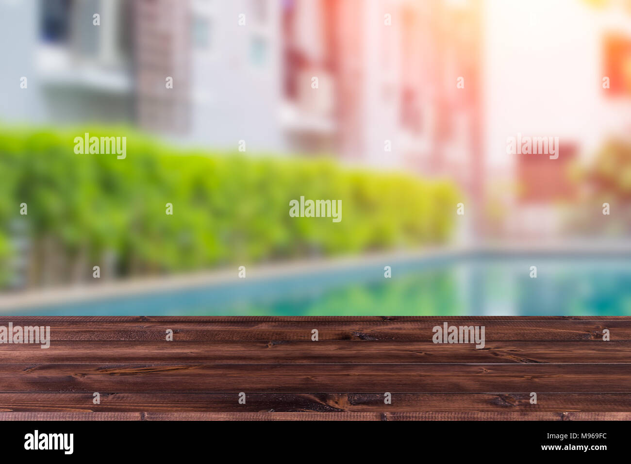 Wooden table with blur condominium pool background in summer times for product show space Stock Photo