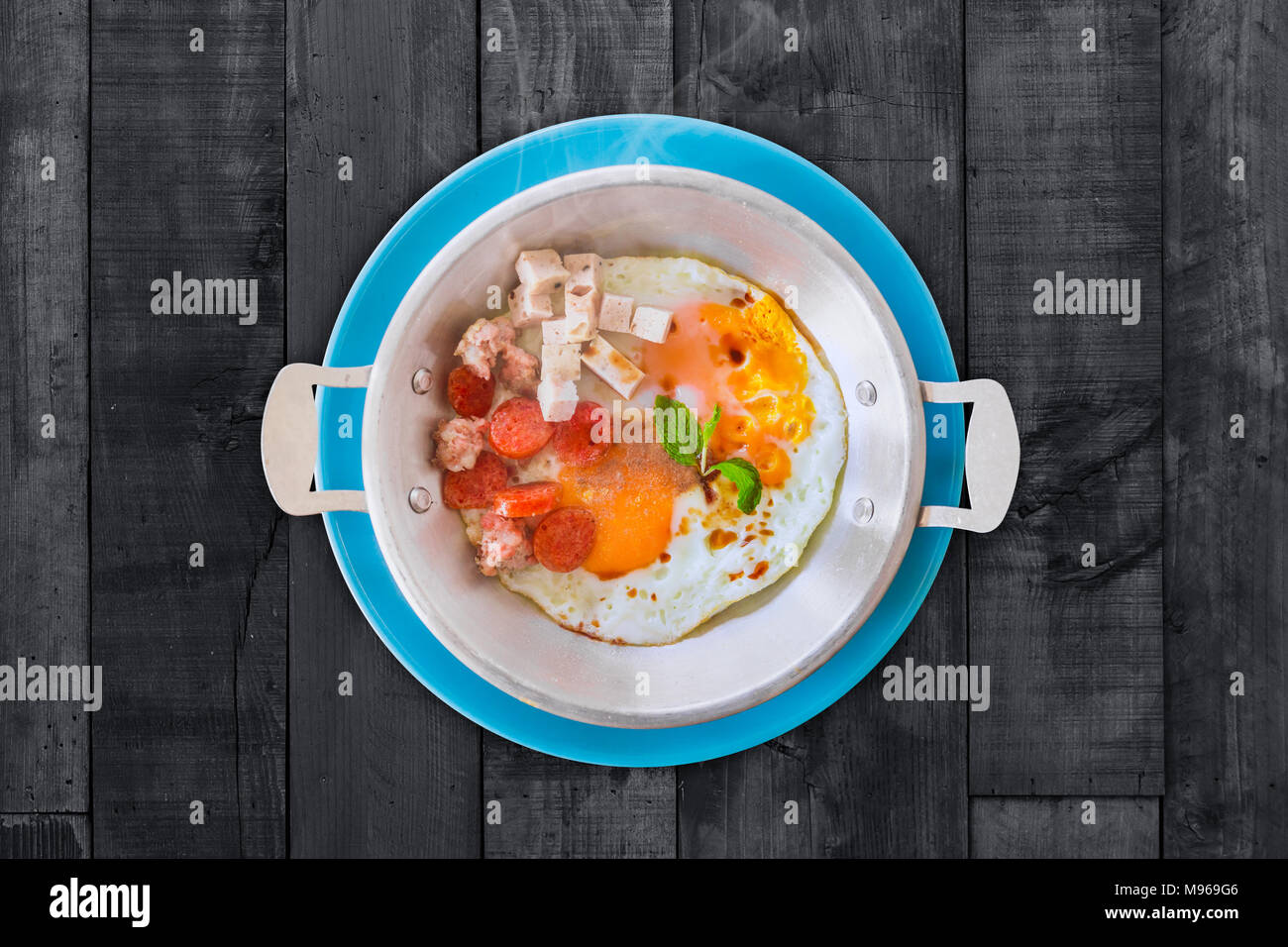 Hot Pan Eggs Recipe - Breakfast Thai Style on black wooden table Stock Photo