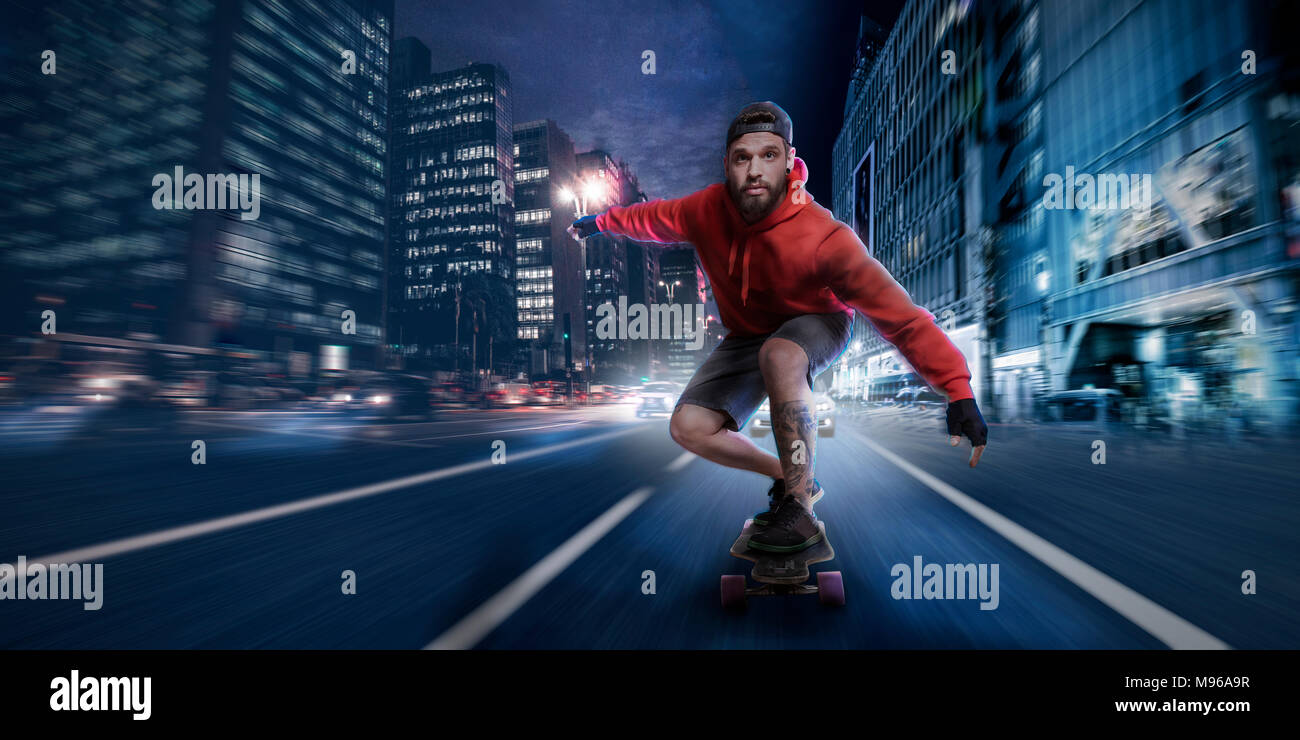 Stylish hipster man in red hoodie shirt and baseball cap cruises with high speed on a longboard in the streets of a downtown district Stock Photo Alamy