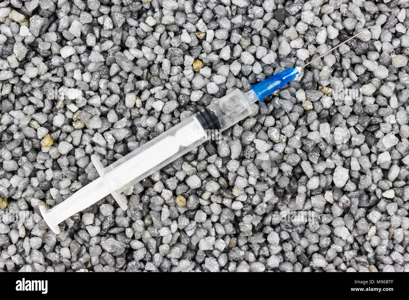 Plastic syringe on the fine gravel. Medicine, medicine. Taking drugs. Stock Photo