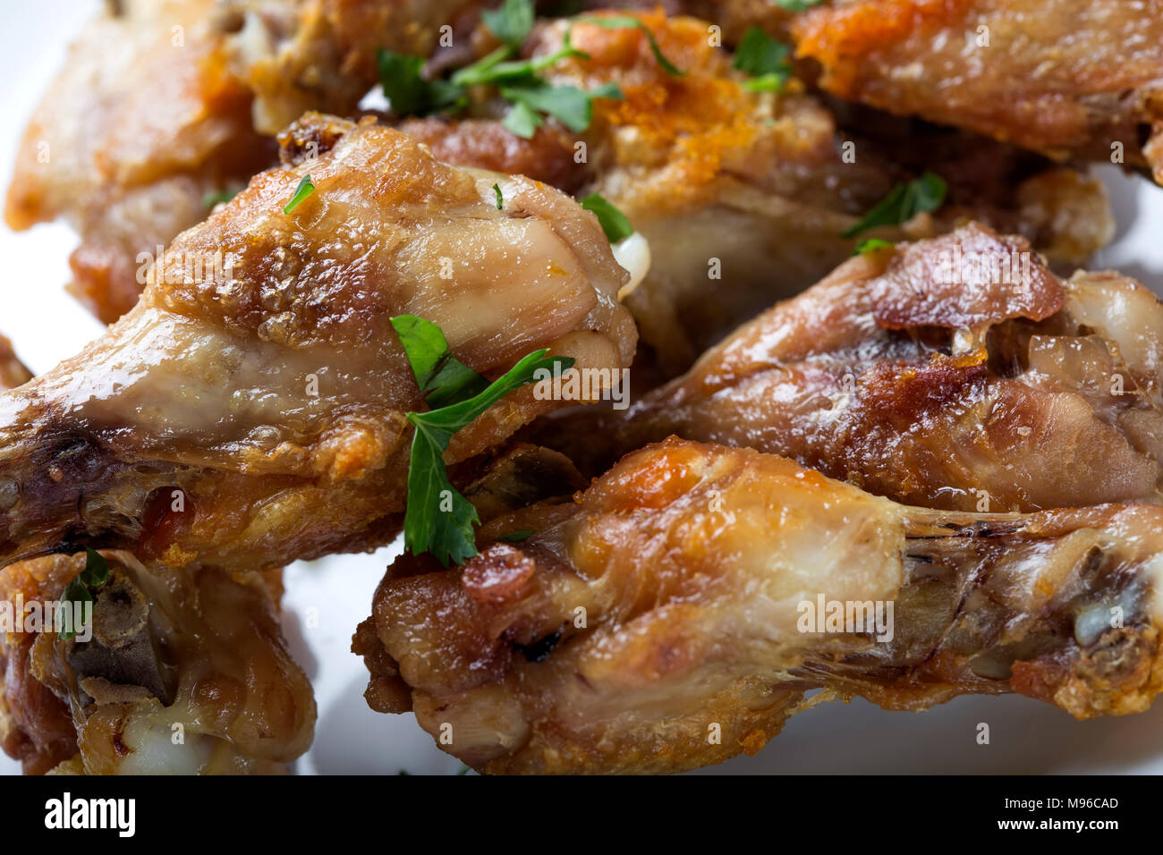 Close up of fresh Grilled chicken drumsticks with parsley leaves on white plate Stock Photo