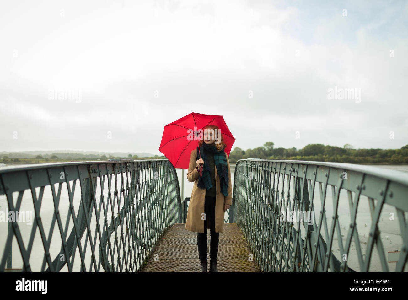 Woman standing with umbrella at railway station Stock Photo Alamy