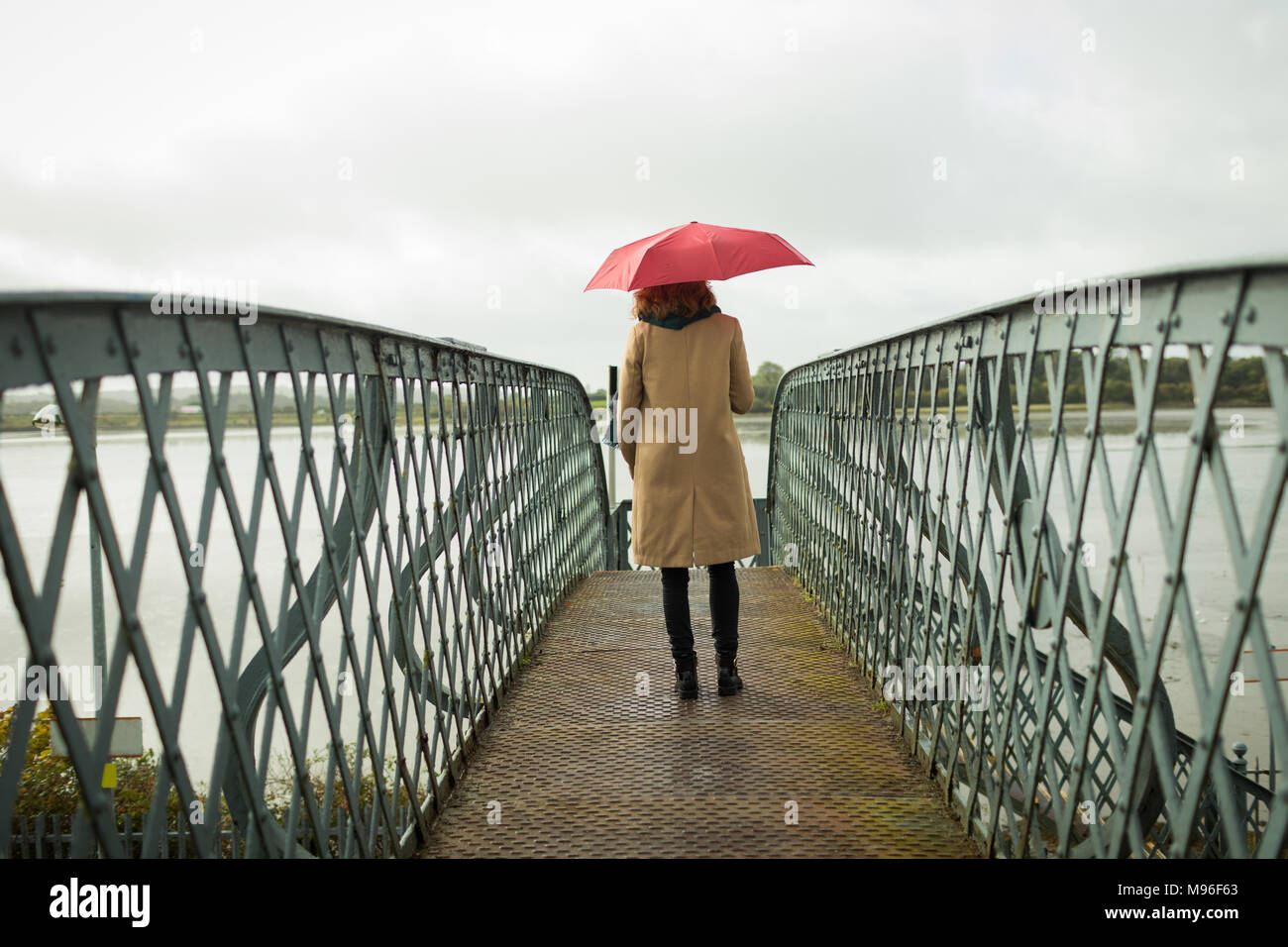 Woman standing with umbrella at railway station Stock Photo Alamy