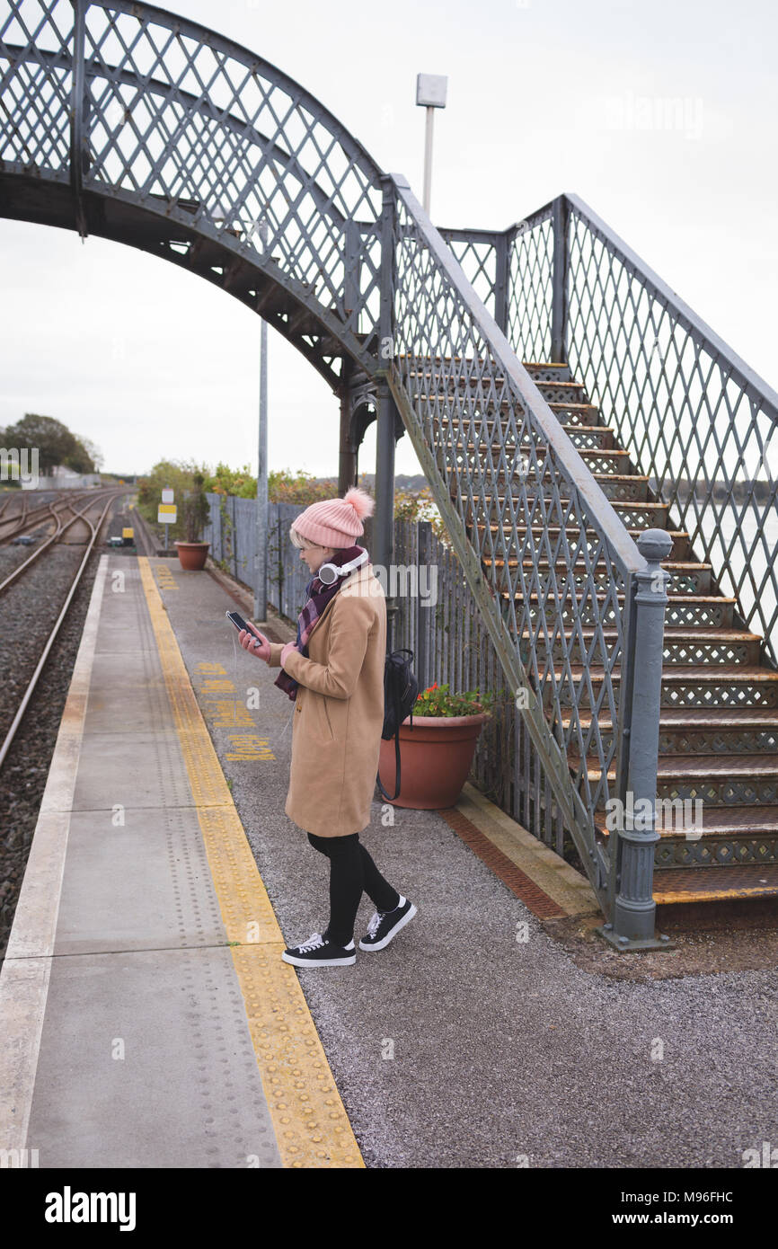 Woman using mobile phone in railway platform Stock Photo