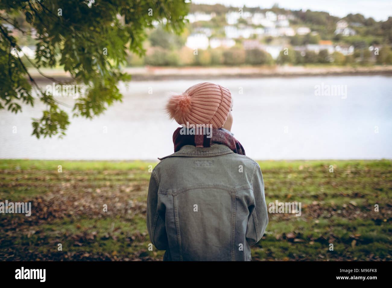 Young woman wearing warm clothing standing near river coast Stock Photo