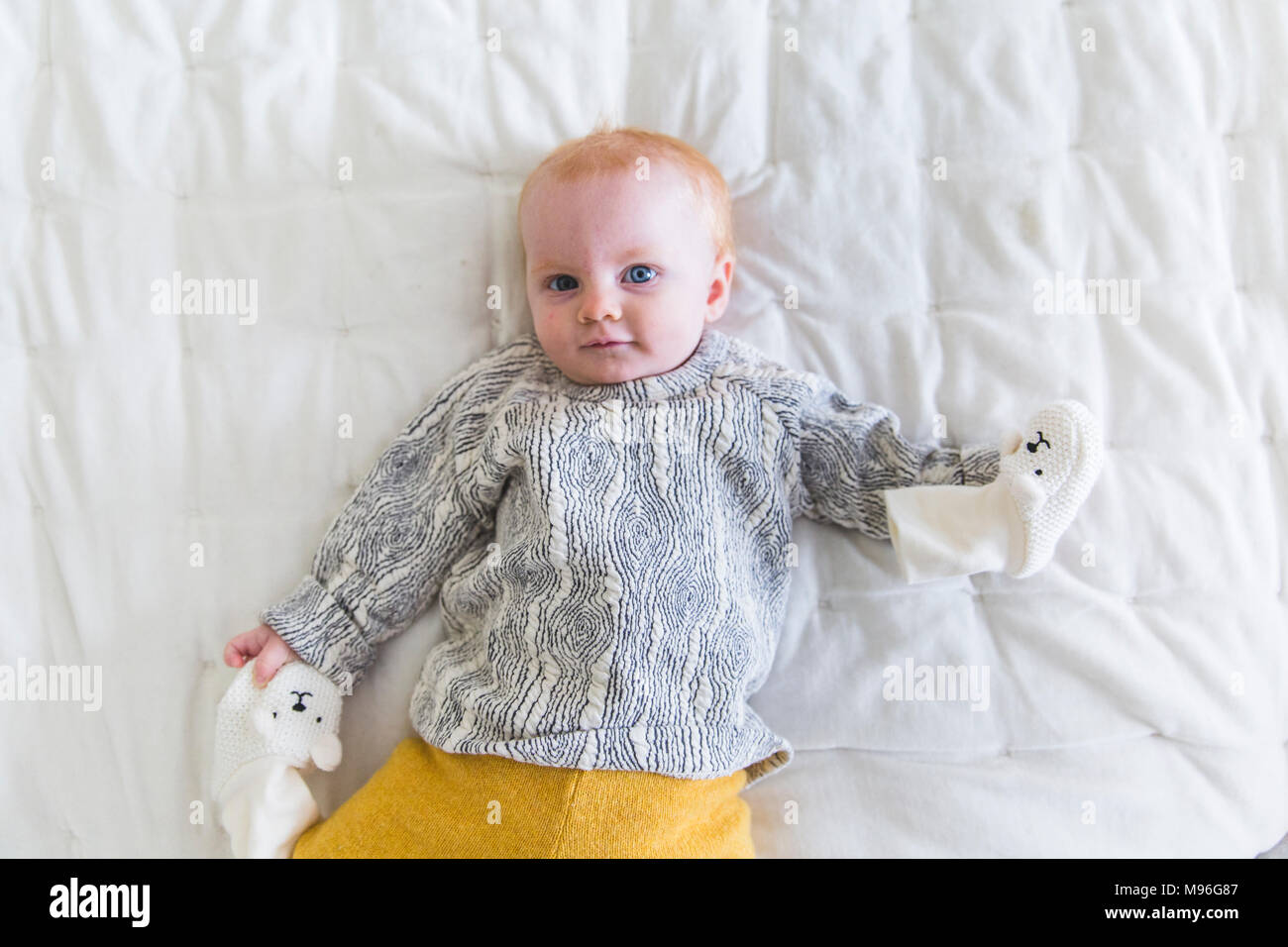 Baby lying on bed with mittens Stock Photo Alamy