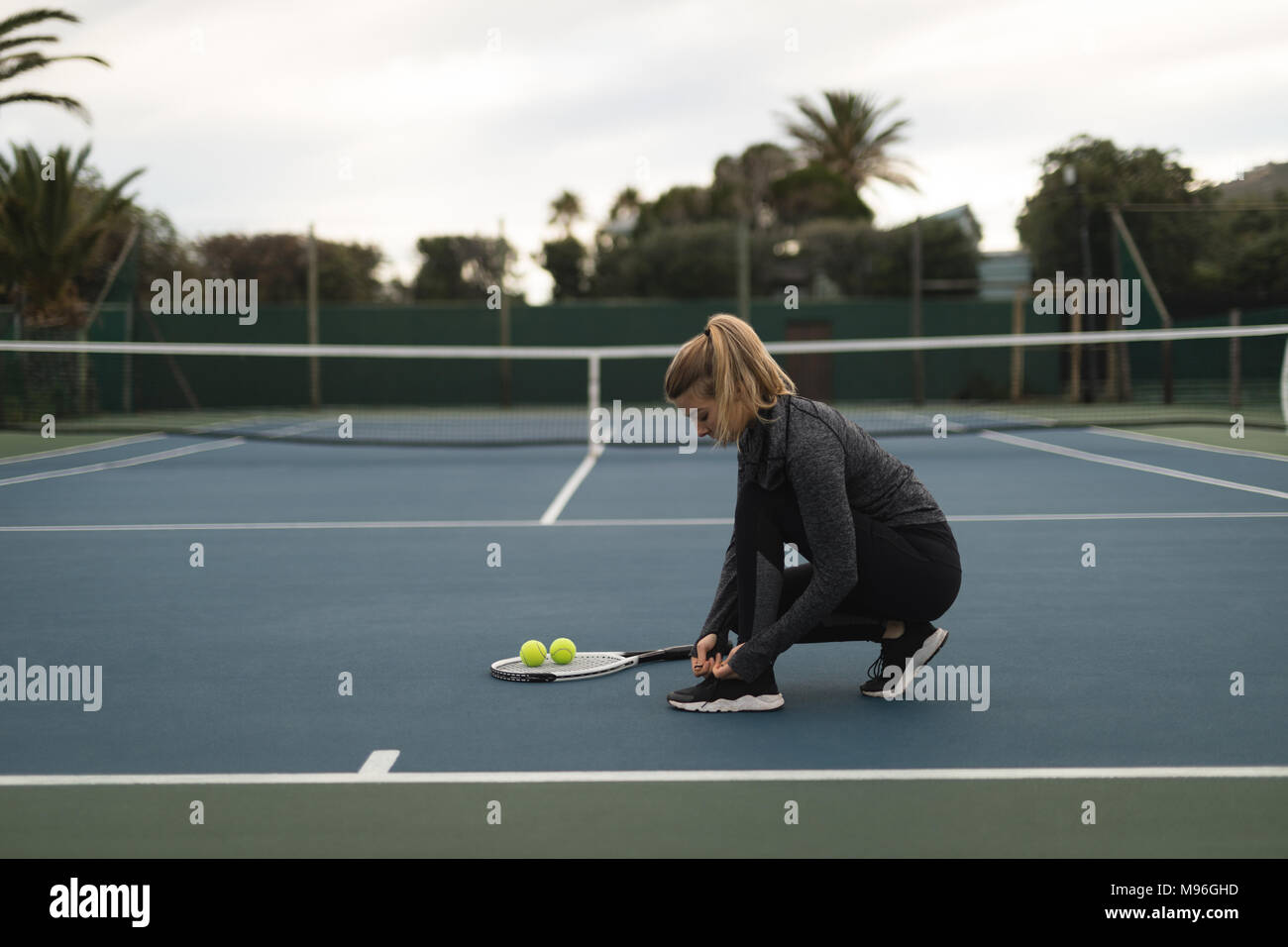 Woman tying her shoelaces in tennis court Stock Photo