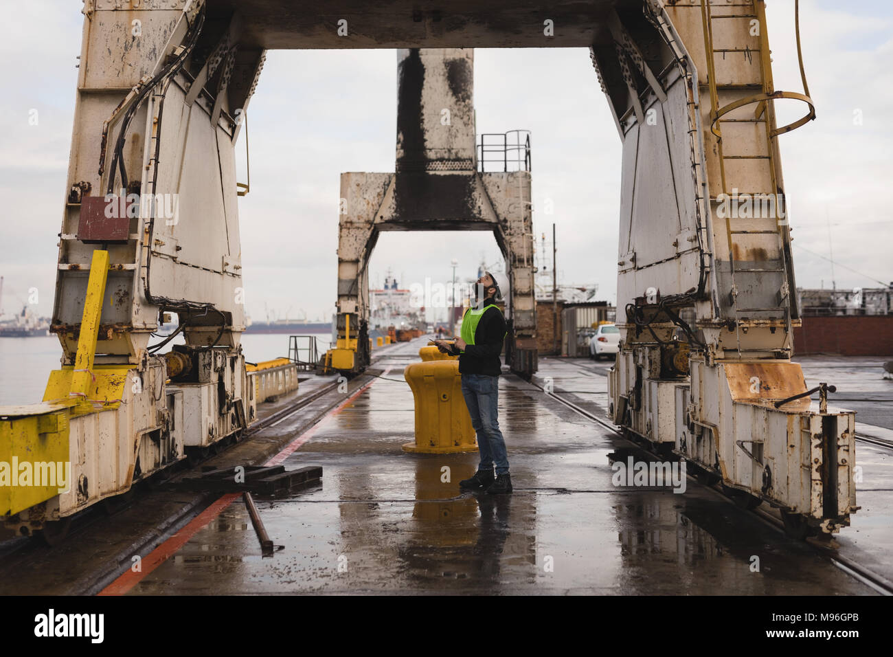 Dock worker inspecting the huge cranes Stock Photo