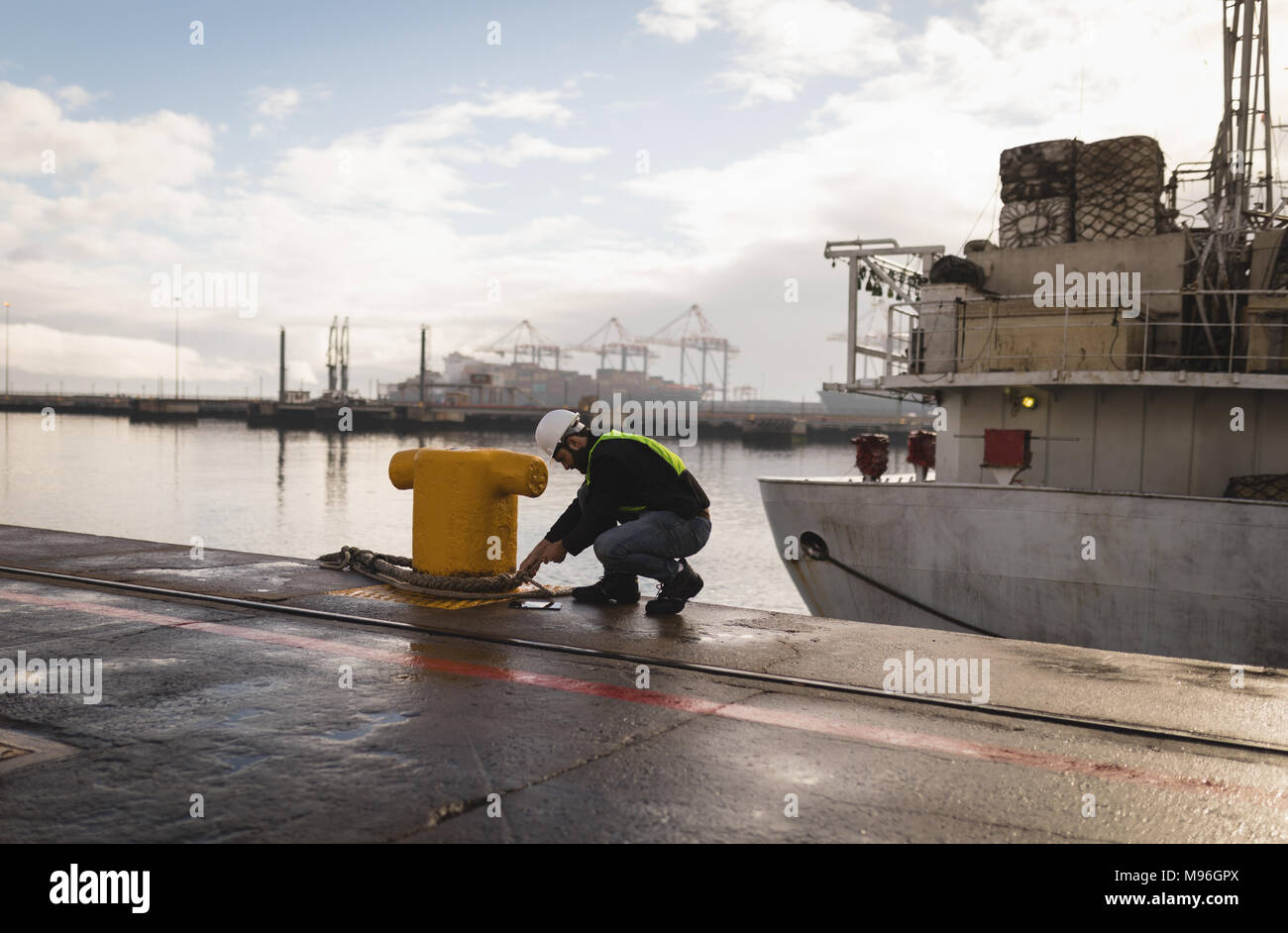 Dock worker tying rope on bollard Stock Photo