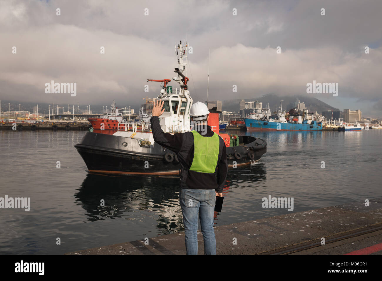 Dock worker waving hand to sailing boat Stock Photo