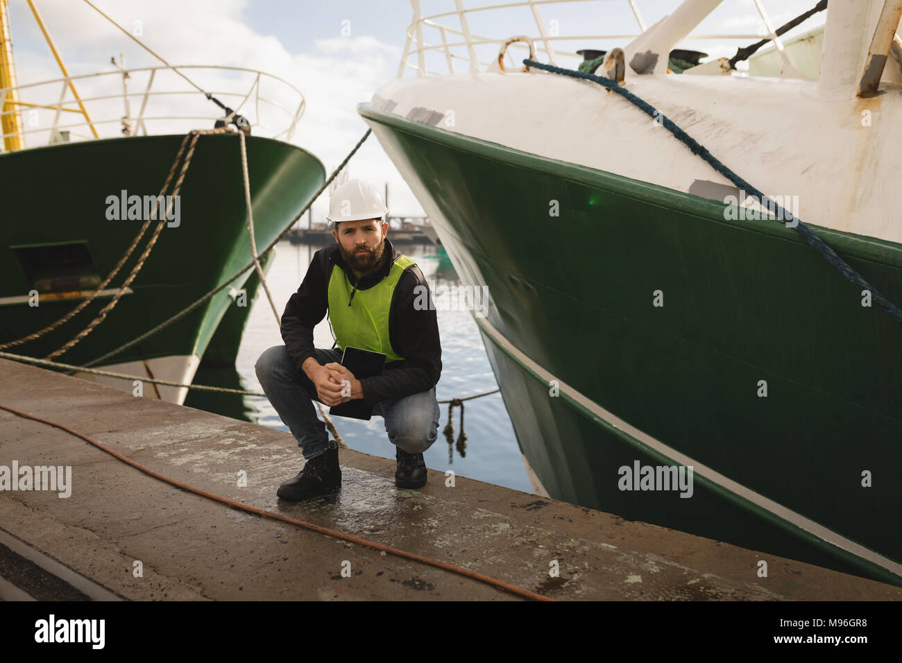 Dock worker posing near ship at port Stock Photo