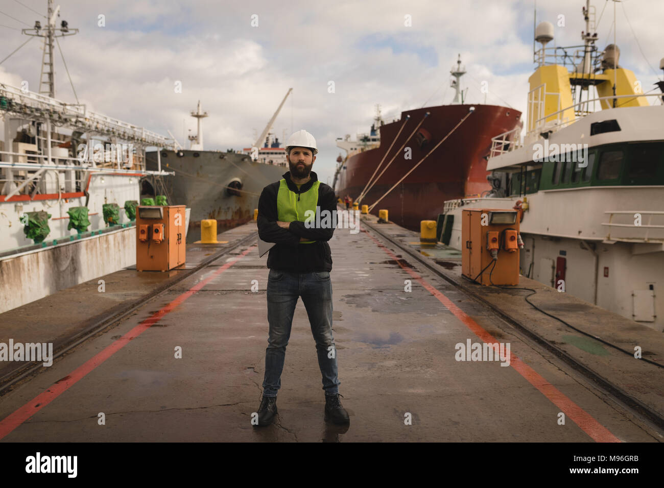 Dock worker standing with arms crossed in shipyard Stock Photo