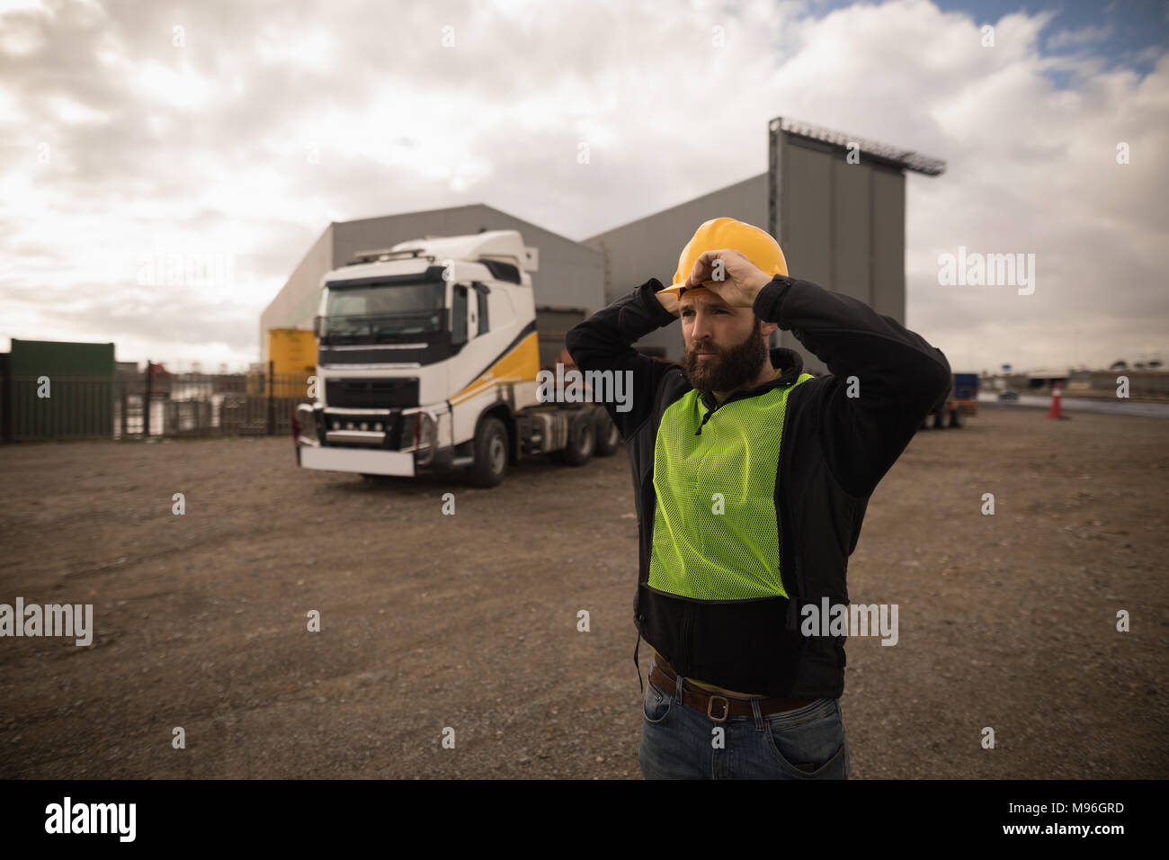 Dock worker adjusting his hard hat in the shipyard Stock Photo