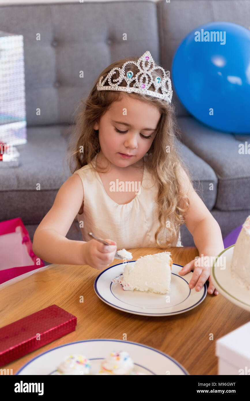 Cute girl having slice of cake in living room Stock Photo Alamy
