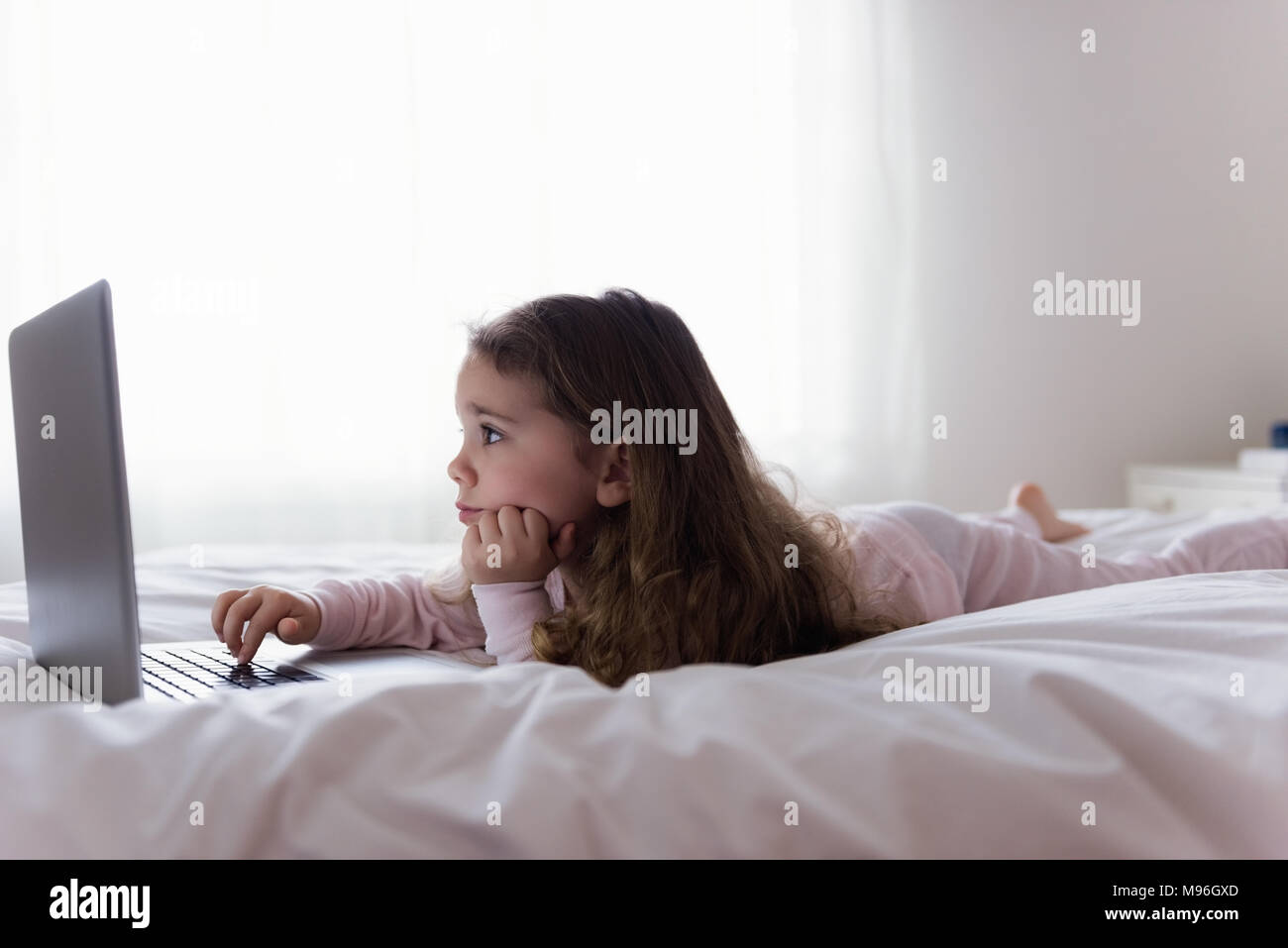 Little girl using laptop in bedroom Stock Photo - Alamy