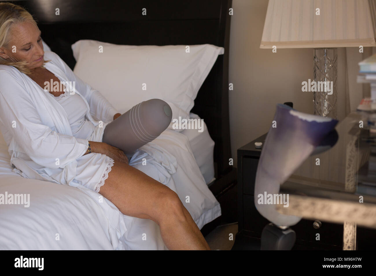 Woman with artificial limb wearing socks in bedroom Stock Photo