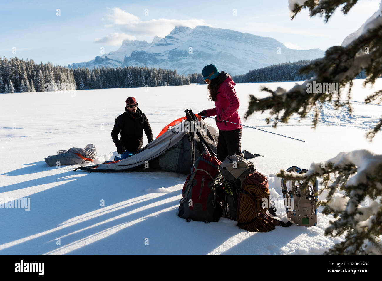 Couple pitching a tent in snowy landscape Stock Photo