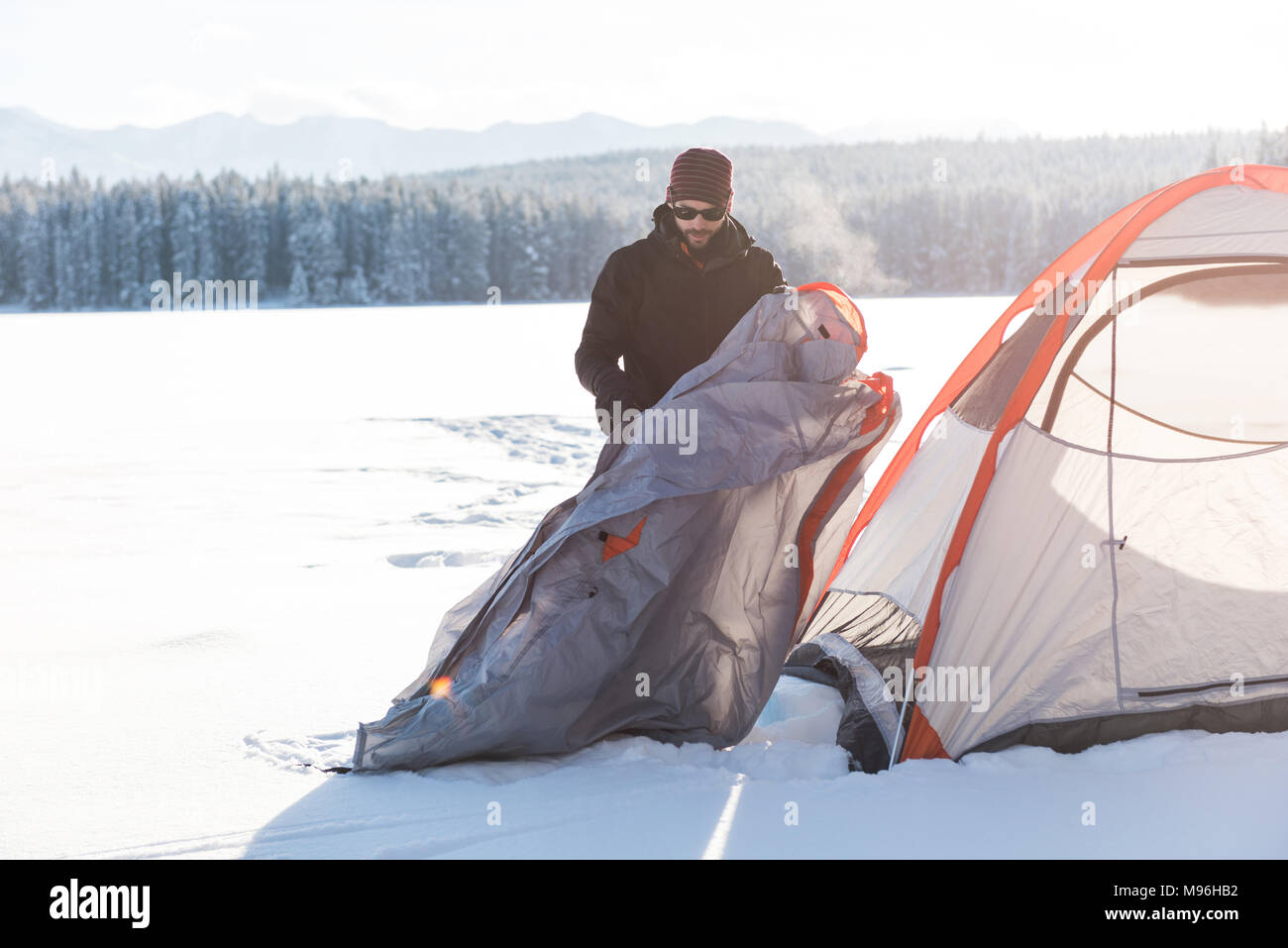 Man pitching a tent in snowy landscape Stock Photo