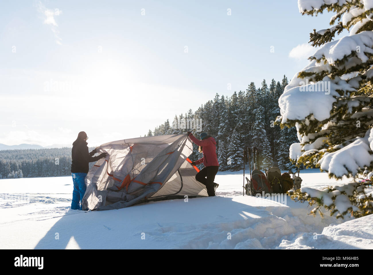 Couple pitching a tent in snowy landscape Stock Photo