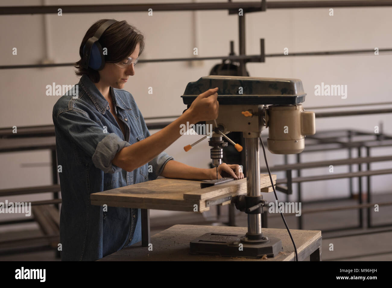 Female welder using vertical drilling machine Stock Photo