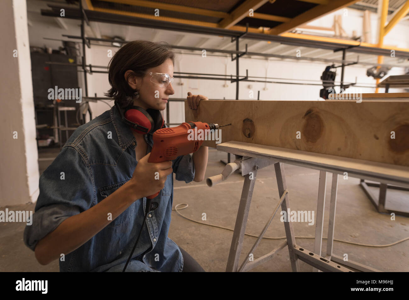 Female welder using drilling machine Stock Photo
